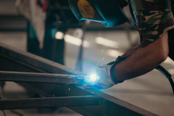 Industry worker welding iron pieces at work