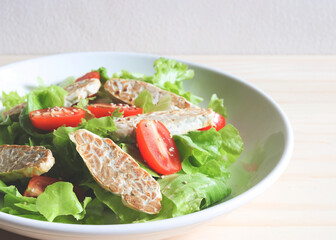 tempeh or tempe salad with tomato and green vegetable.