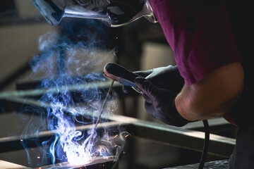 Industry worker welding iron pieces at work