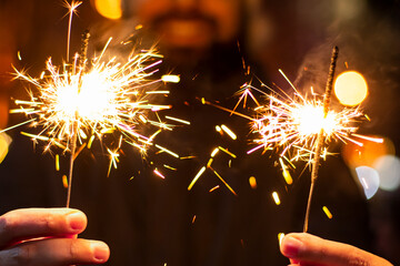 Two sparklers in your hands on a blurred background outside at night. Concept: Merry Christmas. New...
