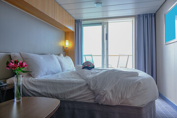 Comfortable double bed with duvet in luxurious oceanview or ocean view or outside or exterior bedroom of balcony veranda cabin or stateroom or suite onboard luxury cruise ship or cruiseship liner