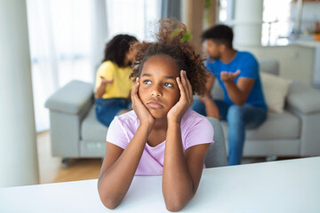 Frustrated little girl feeling depressed while angry parents fighting at home. Worried upset small daughter hurt by fathers and mothers break up or divorce.