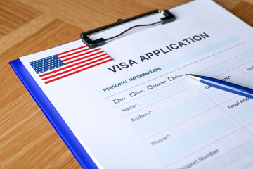 Visa application form for immigration to American flag and pen on table, closeup