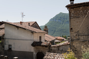 Obraz premium Rustic Italian architecture. Italian village in mountains with traditional buildings, wooden windows, flowers and blooming trees. Aesthetic summer vacation travel concept