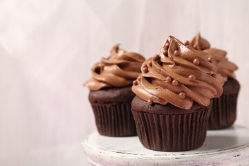 Delicious chocolate cupcakes with cream and beads on white table, closeup