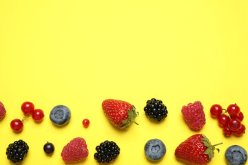 Mix of fresh berries on yellow background, flat lay. Space for text