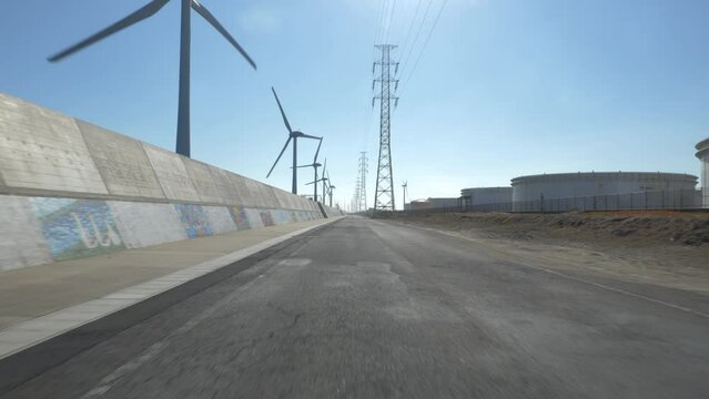 海岸沿いに並ぶ風力発電機と鉄塔沿いの道路を自動車で通り抜ける主観映像