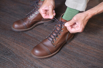 man in green socks tied shoelaces on his new stylish vintage brown work boots