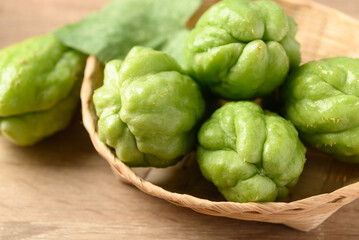 Obraz premium Chayote squash fruit in basket on wooden table, Organic vegetables