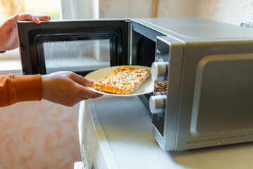 Uncooked frozen small pizza placed into the microwave.junk food,fast food concept.Side...