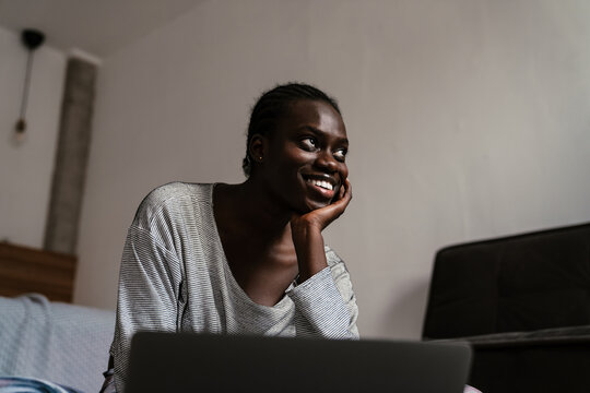 Young african american woman smiling while using laptop at home