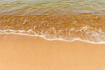 Soft beautiful sea wave on sandy beach. Water bright background.Top view.Copy space.