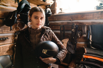 Young jockey woman preparing horse riding in stable