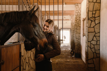 Young blonde jockey woman spending time with her horse