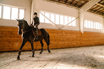 Jockey woman wearing helmet riding her horse during equestrian practice