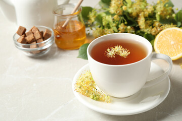 Cup of tea with linden blossom on light grey marble table