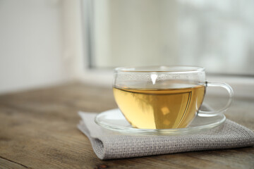 Tasty hot green tea in cup on wooden table
