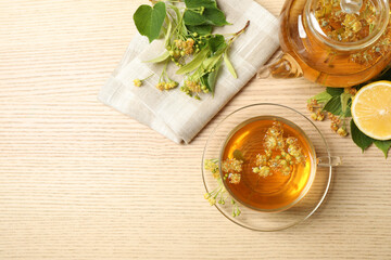 Flat lay composition with tasty tea and linden blossom on wooden table. Space for text