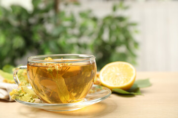 Cup of tea with linden blossom on wooden table. Space for text