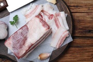 Tasty salt pork with garlic and parsley on wooden table, top view