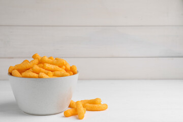 Bowl with crunchy cheesy corn snack on white table, space for text