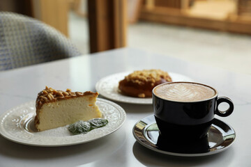 Cup of fresh coffee and desserts on table indoors