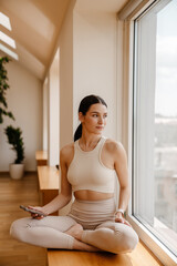 Young white woman using mobile phone during yoga practice