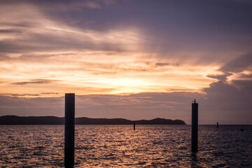 Sunset scene with warning marking steel pole in the sea