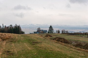 Fototapeta premium A beautiful panoramic landscape of mountains in grey rainy weather in Europe. Wooden summer house, cottage, beautiful nature. Breathtaking view. 