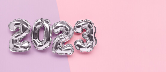 Banner with 2023 silver balloons on a pink and purple background with copy space. New Year's minimal composition.
