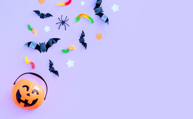 composition on the theme of the holiday halloween bucket pumpkins sweets bats spiders on a purple background with a place for text