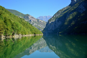 Fototapeta premium Albania, Lake Koman is a reservoir on the Drin River in northern Albania, surrounded by dense forested hills, vertical slopes, deep gorges and a narrow valley