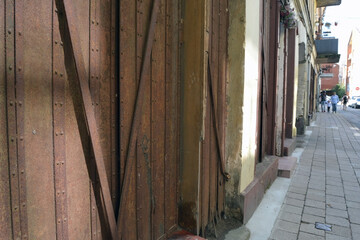 Selective focus of old metal door shutter on blurred street space