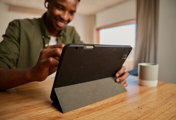 Young adult black African-American male drawing with pen on electronic tablet while working remotely from modern apartment. Graphic designer, digital nomad.