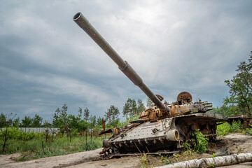 The rusty hull of a broken tank is overgrown with grass.