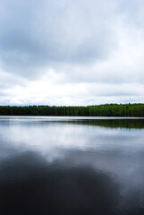 Lake in summer. A lake surrounded by forest. Peat lake. Ripples on the water. Large volume clouds over the water. Cloudy. Natural landscape. The expanses of Russia.