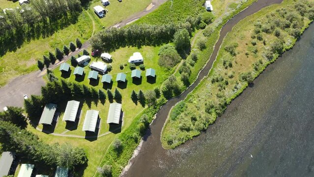 Aerial view of campers close to a beautiful river surrounded by green fields in Iceland