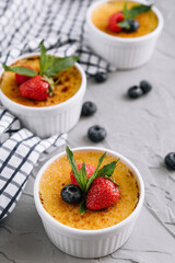 cup of creme brulee with dessert plug and mint leave with berries