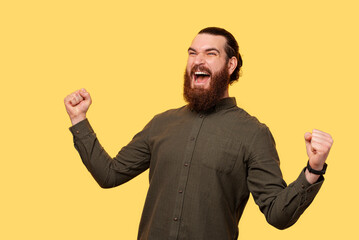 Fototapeta premium An excited bearded man screaming of happiness with his both hands up