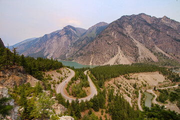 Fototapeta na wymiar Seton Lake Lookout In Lillooet, B.C. The view on the famous U turn surrounded by beautiful mountain and turquoise lake. Hazy sky.