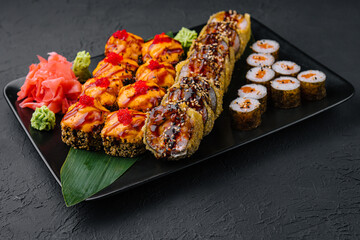 Served warm sushi with ginger and wasabi on a black stone plate