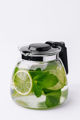 Fruit water with lime and mint in glass pitcher