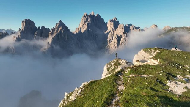 Stunning view of a tourist on the top of a hill enjoying the view of the Cadini di Misurina during a cloudy day. Cadini di Misurina is a group of mountains located in the Dolomites, Italy.	