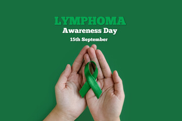 Adult hands holds green ribbon on green background. World lymphoma awareness day. September 15....