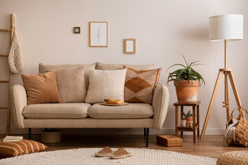 Boho and cozy interior of living room with design beige sofa, pillows, mock up poster frames, side tables, plants, bamboo ladder, decoration and personal accessories. Home decor. Template.