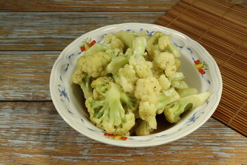 Traditional fried and stirred fresh cauliflower dressing with soy sauce and pepper serving on the plate. Famous vegetarian food menu in Asia.