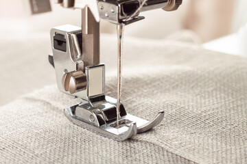 Modern sewing machine presser foot with linen fabric and thread, closeup, copy space. Sewing...