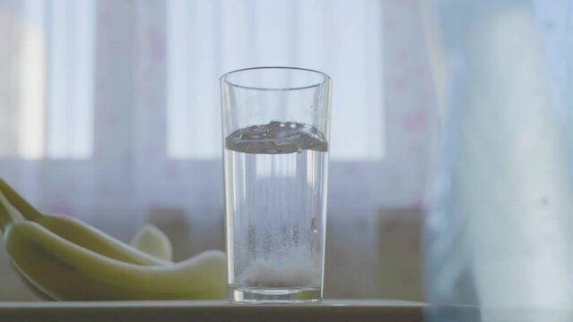 Slowmotion log sparkling vitamin pill drops in glass of water