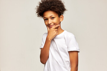 Portrait of smiling tricky pensive teenage boy in white mockup t-shirt with copy space for your...