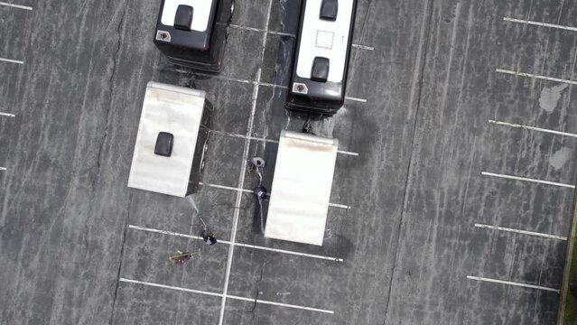 Workers Cleaning And Washing A Bus After A Live Music Tour - Top Down, Aerial